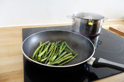 Asparagus in pan on glass-ceramic stove top