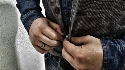 Midsection of man buttoning vest