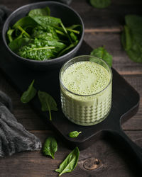 Glass of homemade healthy green smoothie with fresh baby spinach