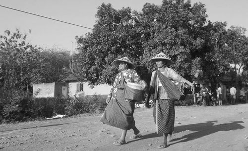 Female friends in traditional clothing walking on field