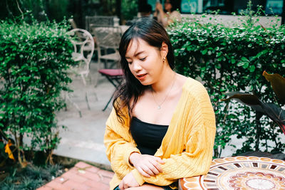 Young woman looking away while sitting outdoors