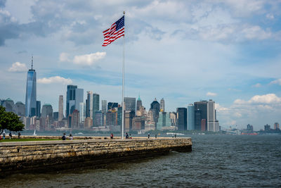 Flag by buildings in city against sky