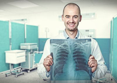 Portrait of smiling doctor holding x-ray image