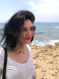 Smiling woman looking away at beach against sky