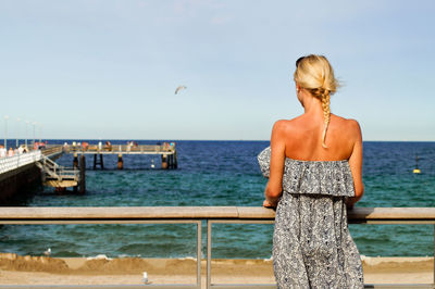 Rear view of woman standing in front of sea