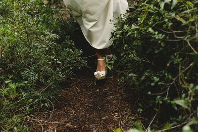 Low section of woman in high heels walking on field