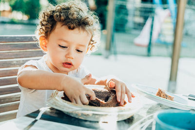 Cute boy eating food on table