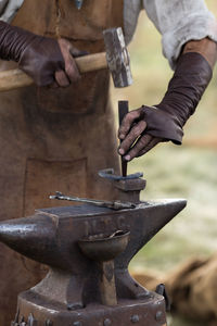 Midsection of blacksmith working at workshop