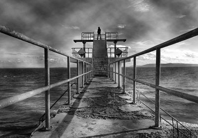 Pier on sea against cloudy sky