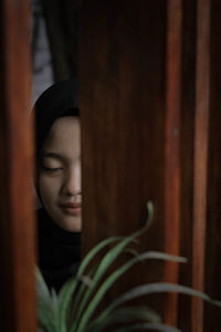 Portrait of young woman looking through window