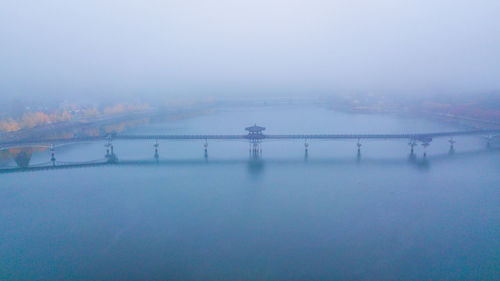 Bridge over frozen lake against sky during winter