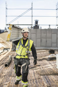 Construction worker carrying metal plank at site