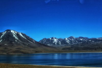 Scenic view of lake and mountains against clear blue sky