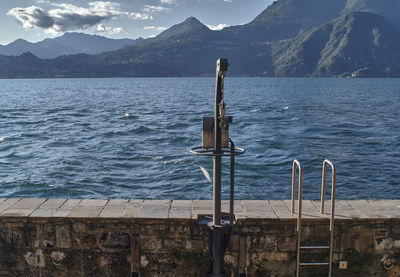Wooden posts in sea against mountains