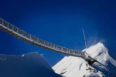 Low angle view of snowcapped mountain against blue sky