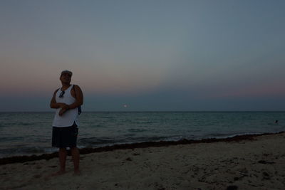 Full length of woman standing on beach against sky during sunset