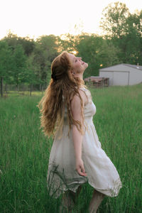 Woman standing on field against trees
