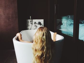 Rear view of woman sitting in bathtub