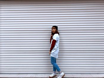 Portrait of boy standing against wall in city