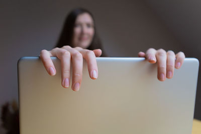 Cropped hand of woman closing laptop