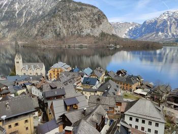 Houses by lake and mountains against sky