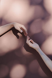 Cropped hands of man and woman gesturing against wall