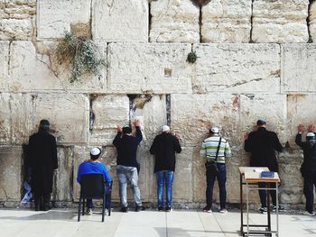 Rear view of people standing against wall