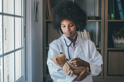 Smiling doctor examining stuffed toy at clinic