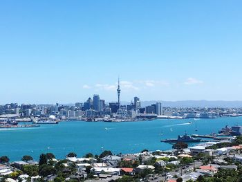 View of city at waterfront against blue sky