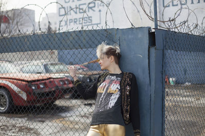 Woman looking away while standing on chainlink fence