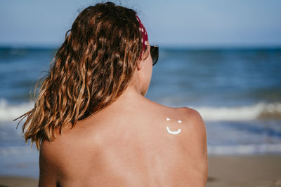 Rear view of woman at beach against sky