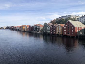 Buildings by river against sky