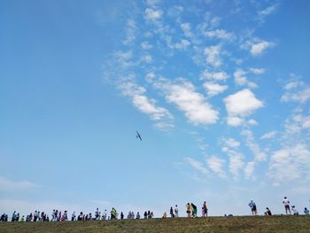 Group of people flying against blue sky