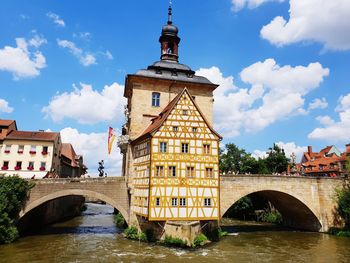 Arch bridge over river amidst buildings against sky