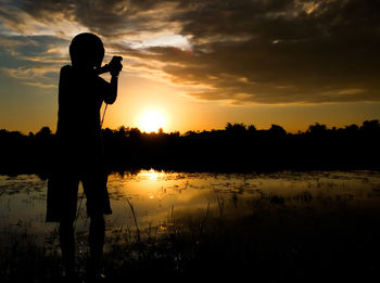 Silhouette man standing against sky during sunset