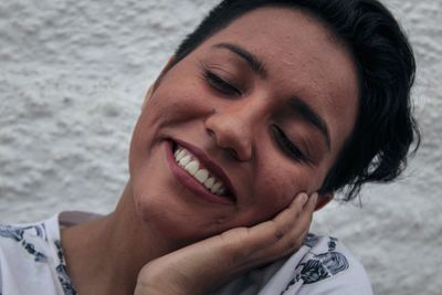 Close-up portrait of a smiling young woman with eyes closed