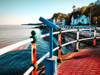 Railing by sea against clear blue sky