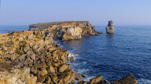 Rock formation in sea against clear sky