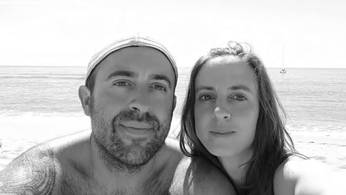 Portrait of couple at beach against sky