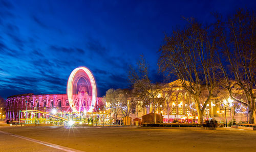 Illuminated ferris wheel against sky at night