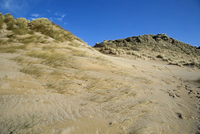 Low angle view of sand dunes against clear sky