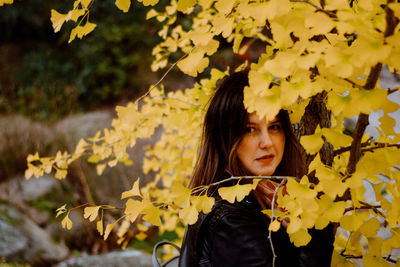 Close-up of young woman with yellow leaves