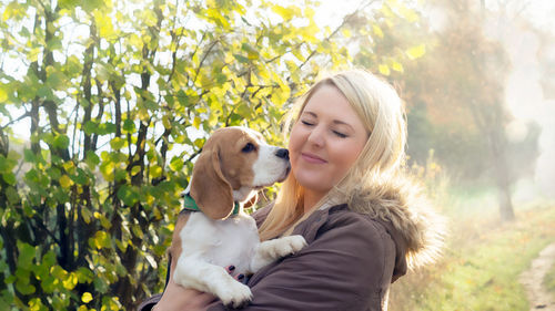 Portrait of woman with dog against plants