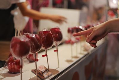 Cropped hand of person pointing at taffy apple at store