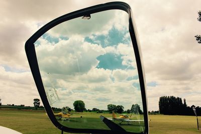 Trees on field against cloudy sky