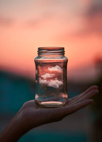 Close-up of hand holding glass of clouds