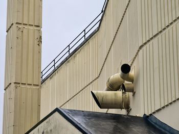 Rear view of man sitting on wall against sky