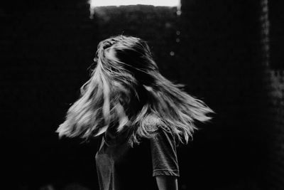 Young woman shaking head while standing outdoors at night