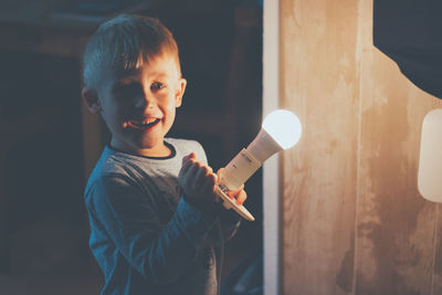 Smiling boy holding illuminated light bulb