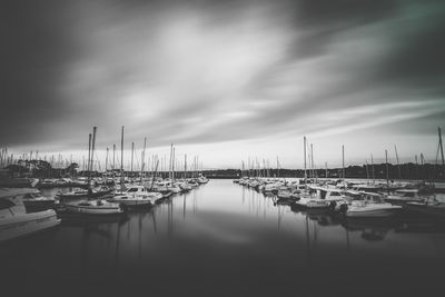 Boats moored at harbor against sky